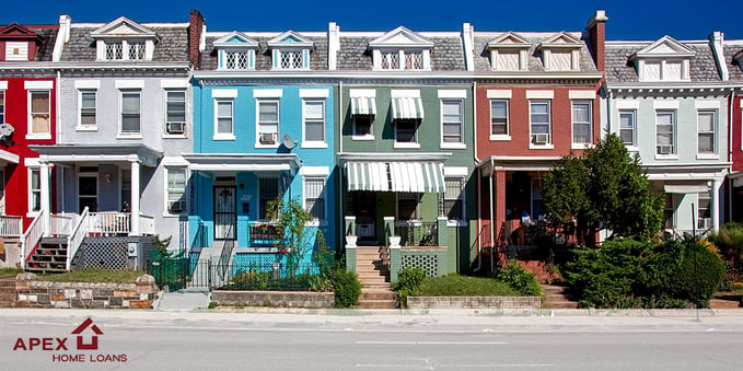 A photo of some colorful town homes together on a street.